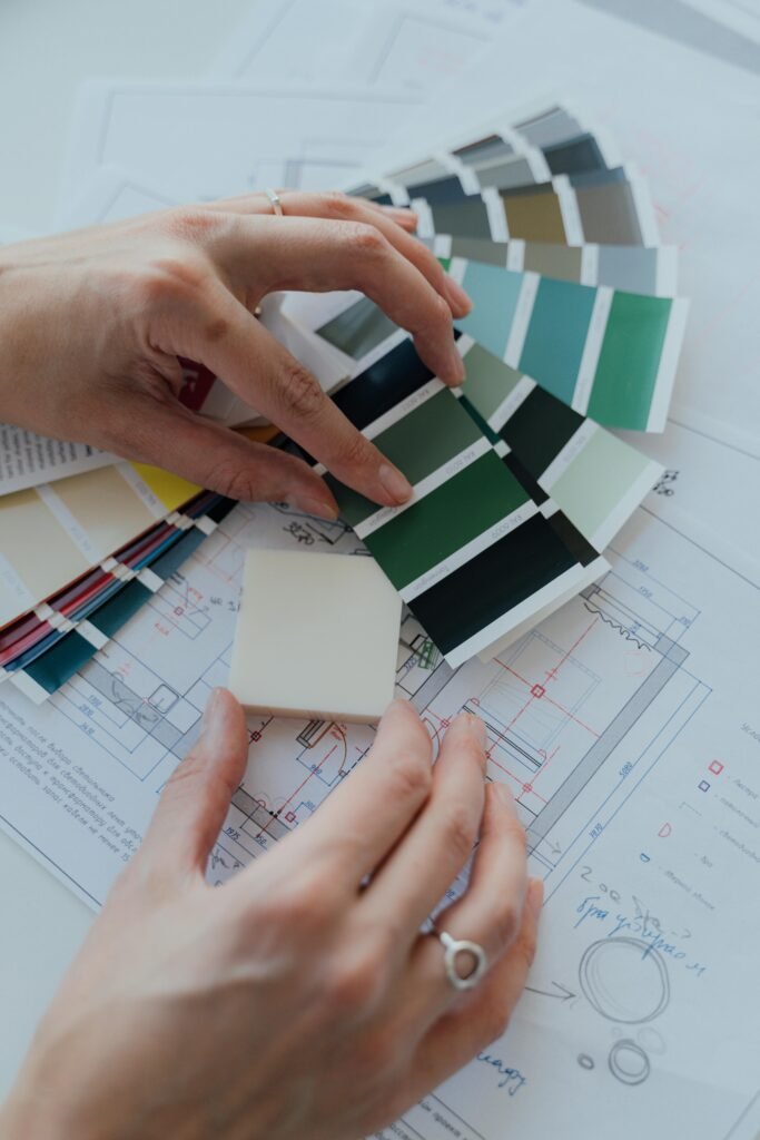 Ortecho Construcciones Calle Jacobina - Jacobina Hands selecting color samples over architectural plans for interior design.